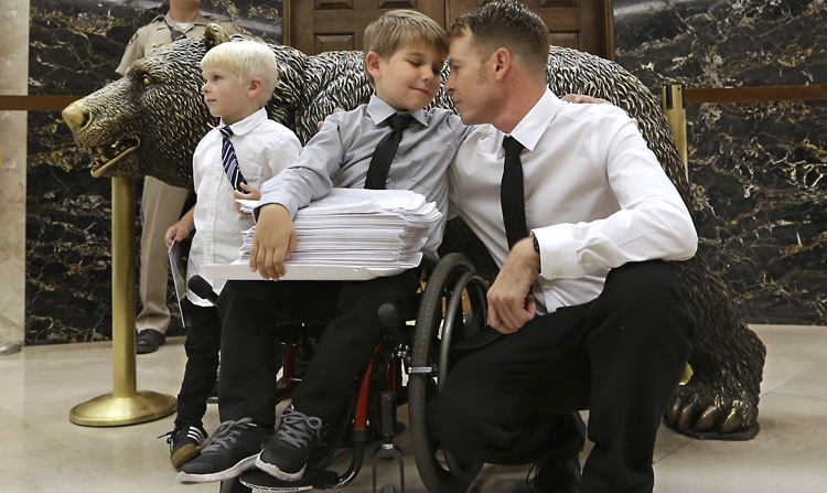 Otto Coleman, 6, waits outside the Governor's office with his brother Fenton, 4, left, and father Joshua, to deliver a stack of petitions with thousands of signatures calling on California Gov. Jerry Brown to veto a measure requiring nearly all California school children to be vaccinated Monday, June 29, 2015, in Sacramento, Calif. The state Senate approved the bill sending it to Brown. Joshua Coleman said his son has been wheelchair bound as a result of an adverse reaction to a vaccine. Photo: AP